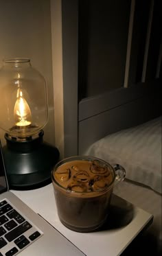 an open laptop computer sitting on top of a desk next to a glass jar filled with liquid