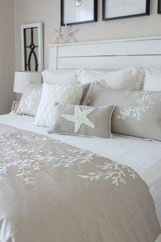 a white bed topped with lots of pillows next to two framed pictures on the wall