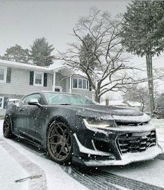 a car is parked in the snow near a house