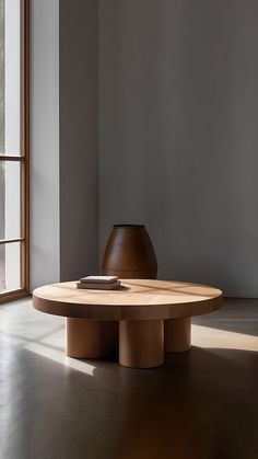 a wooden table sitting in front of a window next to a vase on the floor