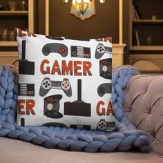 a couch with a blanket on top of it and a pillow that has video game controllers printed on it