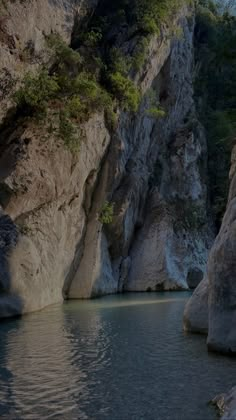 there is a boat that is going through the water near some rocks and trees in the background