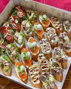 an open box filled with lots of different types of appetizers on top of a wooden table