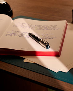 an open notebook with a pen sitting on top of it