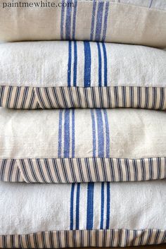 four blue and white striped towels stacked on top of each other in front of a wooden table