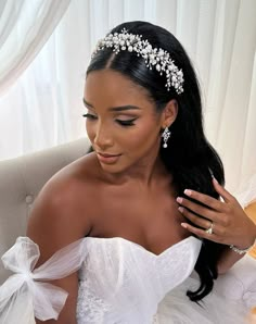 a woman in a wedding dress sitting on a couch wearing a bridal headpiece