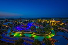 an aerial view of a resort at night with lights on the pool and surrounding grounds