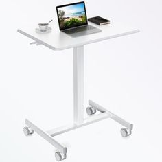 a laptop computer sitting on top of a white table next to a cup and saucer