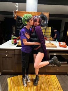 two people dressed up as the joker and harley kissing in front of a kitchen counter