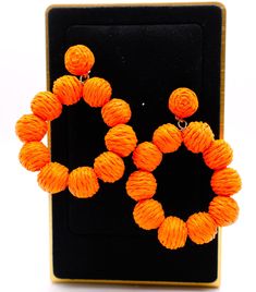 These striking hoop earrings capture the essence of a vibrant sunset on a tropical beach. Designed with bright orange straws that form the hoop, each earring is adorned with small orange balls for an extra touch of playful elegance. The result is a captivating statement piece that can instantly transform any outfit, making it stand out with a burst of color and lively charm. Length: 3 inches Care: Avoid contact with water and cosmetics, such as creams or perfumes. To restore the luster and shine Orange Earrings For Spring Beach Outing, Orange Dangle Jewelry For Spring, Spring Orange Drop Earrings, Orange Spring Vacation Jewelry, Orange Drop Earrings For Beach, Orange Drop Earrings For The Beach, Orange Summer Earrings For Vacation, Vibrant Orange Summer Earrings, Orange Dangle Earrings For Beach