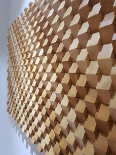 a wall made out of wooden blocks on top of a white wall with a light in the background