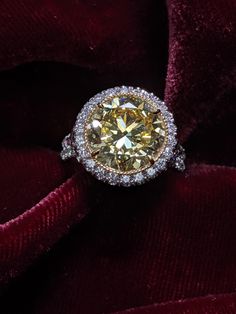 a fancy yellow diamond ring on top of a red velvet