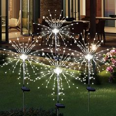 fireworks are lit up in the grass near a house at night with patio furniture and flowers