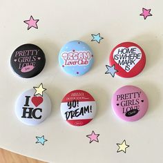 six buttons with different designs on them sitting on a table next to stars and confetti