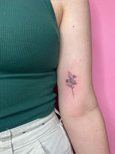 a woman's arm with a small flower tattoo on the left side of her arm