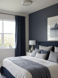 a bedroom with blue walls and white bedding in front of a large window that has curtains