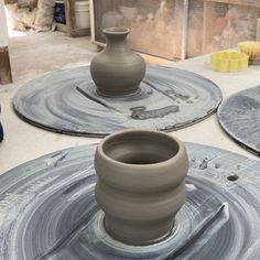 three clay pots sitting on top of each other in front of some circular plates with wheels