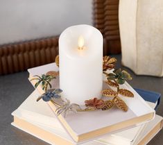 a white candle sitting on top of a stack of books