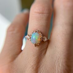 a woman's hand holding an opal ring