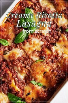 a casserole dish with meat and cheese on it, topped with basil leaves