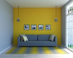 a living room with yellow walls and blue couch in the center, three framed pictures on the wall