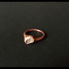 a close up of a ring on a black surface with a small diamond in the middle