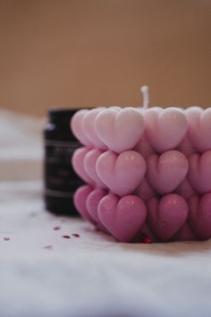 a candle that is made out of hearts on a white tablecloth with confetti scattered around it