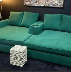 a green couch sitting next to a stack of boxes on top of a blue carpet