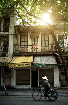 a person riding a bike down the street in front of a building with an awning