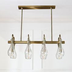 three light chandelier with clear glass bulbs hanging from it's brass frame