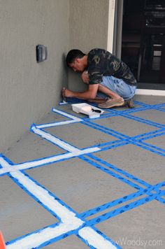 a man is painting the outside of a house with blue tape and paint on it