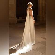 a woman in a white wedding dress standing on a stone floor with her back to the camera