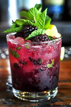 a close up of a drink on a table with fruit and mint garnish