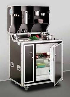 a kitchen cart with an open door and shelves on the side, in front of a gray wall