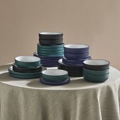 a table topped with lots of plates on top of a cloth covered table next to a wall