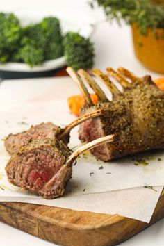 a piece of meat on a wooden cutting board next to broccoli and carrots