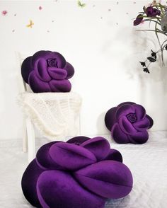 purple flowers sitting on top of a bed next to a white chair