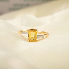 a yellow diamond ring sitting on top of a white cloth