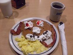 a plate with eggs, bacon and pancakes on it next to a cup of coffee