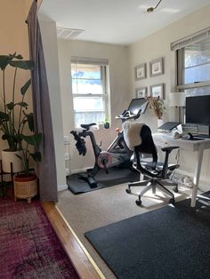 an exercise bike in the corner of a room with a desk and computer on it