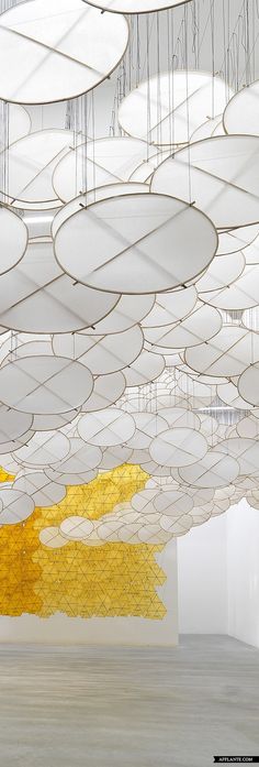 a room filled with lots of white and yellow circles hanging from it's ceiling