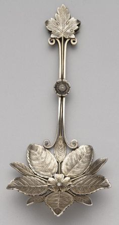 an antique silver spoon with leaves on it