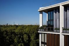 an apartment building overlooks the trees in front of its glassed windows and balconies