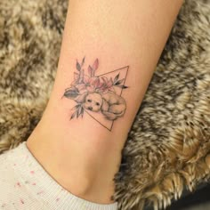 a small tattoo on the ankle of a woman's leg with flowers and leaves