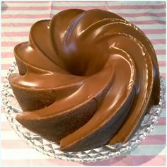 a cake with chocolate icing on top of a glass plate and striped table cloth