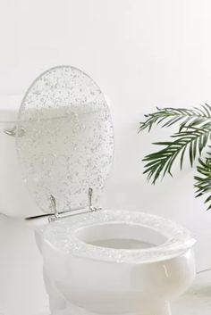 a white toilet sitting next to a potted plant