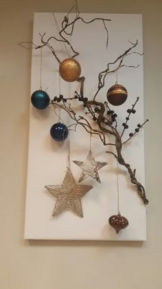 an ornament tree with ornaments hanging from it's branches in front of a white wall