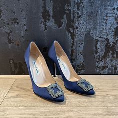 a pair of blue high heeled shoes sitting on top of a wooden floor next to a wall