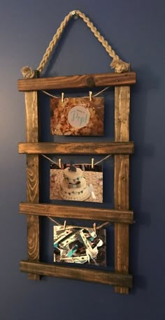 a wooden frame with pictures hanging from it's sides and rope on the wall