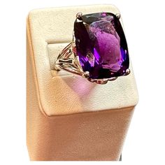 This vintage cocktail ring is a stunning piece of jewelry that features a huge 38 carat cushion-cut natural amethyst set in platinum. The amethyst measures 17 x 21 mm, giving the ring a substantial size and presence. The weight of the ring with the stone is 23.8 grams, adding to its luxurious feel and value. The beautiful work on the side of the band and on the side of the ring adds to the unique beauty of this piece. The craftsmanship is evident in every detail, making this ring a true work of Luxury Amethyst Cushion Cut Ring For Formal Occasions, Luxury Amethyst Cushion Cut Ring For Formal Events, Luxury Cushion Cut Amethyst Ring For Formal Occasions, Formal Amethyst Cushion Cut Jewelry, Formal Cushion Cut Amethyst Jewelry, Luxury Purple Amethyst Ring, Rectangular Shape, Classic Purple Cushion Cut Rings, Luxury Purple Amethyst Rectangular Ring, Luxury Purple Rectangular Amethyst Ring